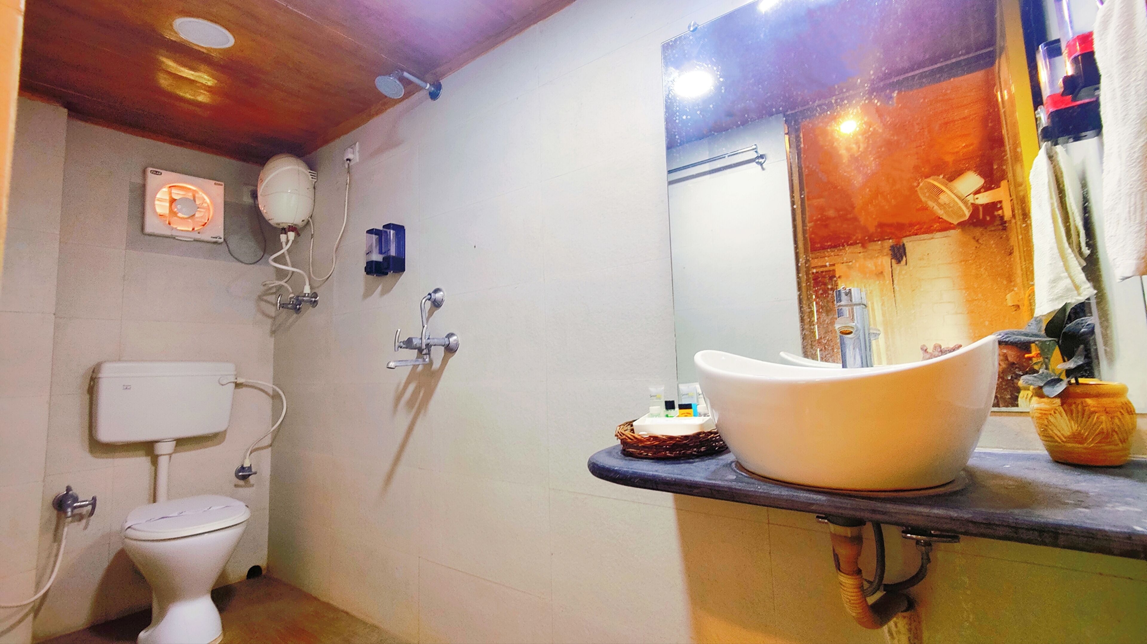 Un baño con inodoro, lavamanos, ducha y espejo.