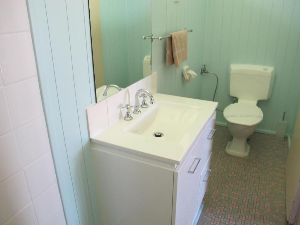A bathroom with a white sink, a mirror, a towel rack, a toilet, and a shower area.