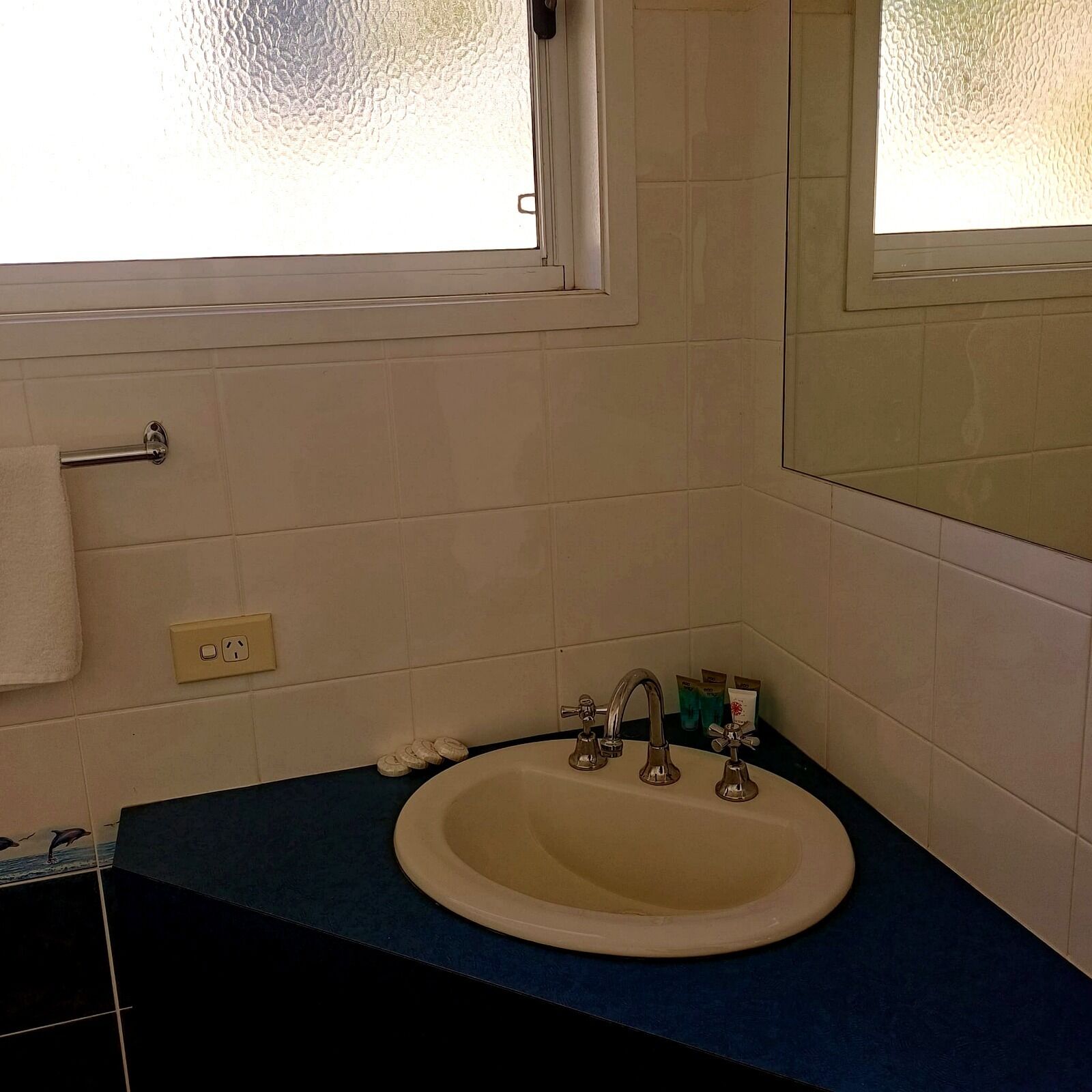 A bathroom with a sink, mirror, and window.