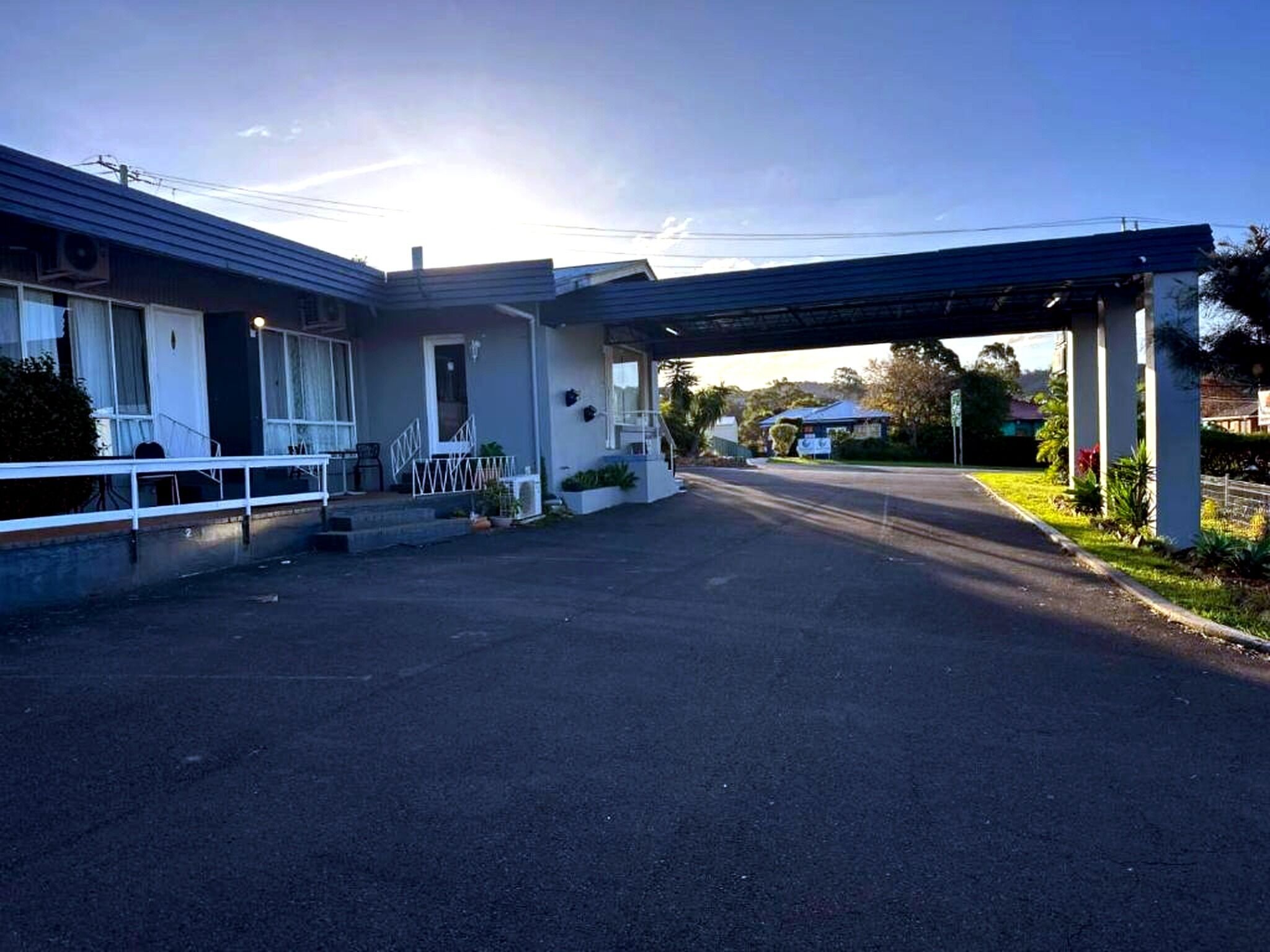 Ein zweistöckiges Hotel mit überdachtem Parkplatz und blauem Himmel.