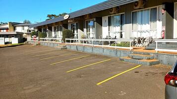 A motel with a parking lot, outdoor seating, and a fire extinguisher.