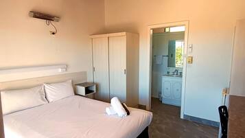 Un dormitorio con cama, mesita de noche y ventilador de techo.