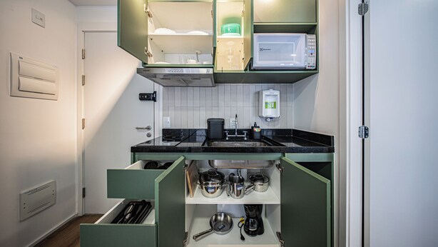 Cozinha compacta com micro-ondas, pia e armários.