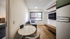 Cozinha compacta com área de refeições, forno embutido e janela com vista para o exterior.