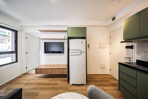 A modern kitchen with a built-in fridge, a microwave, and a stove. There is a window providing natural light and a door leading to another room. - LA CASA PÁSSAROS (São Paulo)