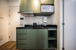A compact kitchen with a microwave, stove, and sink. - LA CASA PÁSSAROS (São Paulo)
