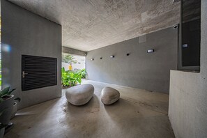 A modern interior with concrete walls, a ceiling, and a floor. There are two large, round, light-colored stools. - LA CASA PÁSSAROS (São Paulo)