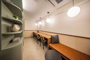 A modern meeting room with a long table, chairs, a bench, and pendant lighting. - LA CASA PÁSSAROS (São Paulo)