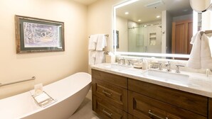Un baño moderno con una bañera independiente, un espejo grande y un cuadro enmarcado en la pared.