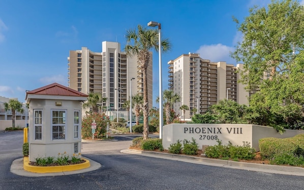 En grind med en skylt som visar texten ”PHOENIX VIII 27008”, höga bostadshus och en liten säkerhetskiosk.