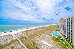 Una località balneare con spiaggia, piscina e edifici a grattacielo.