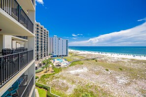 Ein Strandhotel mit mehreren Balkonen, einem Pool und Blick auf den Strand.