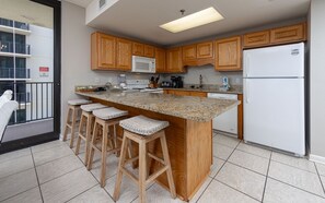 Eine Küche mit Holzschränken, einem weißen Kühlschrank, einer Mikrowelle und einer Arbeitsplatte aus Granit.