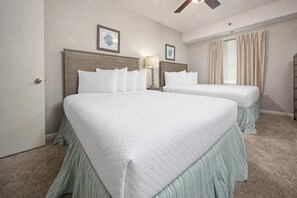 Ein Hotelzimmer mit zwei Betten, einem Deckenventilator und einem Fenster mit Vorhängen.