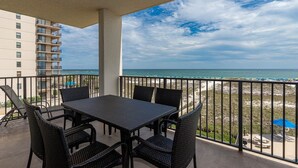 A balcony with a table and chairs, overlooking a beach and ocean. - Phoenix Viii 8306 3 Bedroom Condo (Orange Beach)