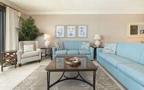 Ein Wohnzimmer mit Sofa, Sesseln, Couchtisch und Wanddekoration.