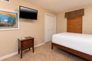 A bedroom with a bed, a TV mounted on the wall, a small bedside table, and a door. - Phoenix Vii 7708 3 Bedroom Condo (Orange Beach)
