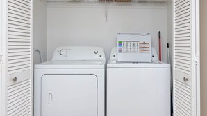 Ett kompakt tvättrum med en tvättmaskin och en torktumlare med frontmatning, en kontrollpanel och en röd penna på torktumlaren.
