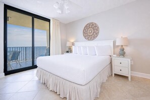 Ein Schlafzimmer mit einem großen Bett, einem Nachttisch, einer Wanddekoration und Meerblick durch eine Schiebetür.