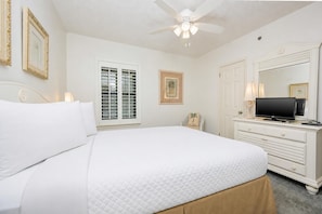 A bedroom with a bed, a TV, a dresser, a ceiling fan, and a window with blinds. - Phoenix Viii 8703 3 Bedroom Condo (Orange Beach)