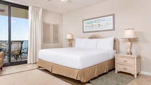 A bedroom with a large bed, two bedside tables with lamps, a view to the outside, and a painting on the wall. - Phoenix Viii 81003 3 Bedroom Condo (Orange Beach)
