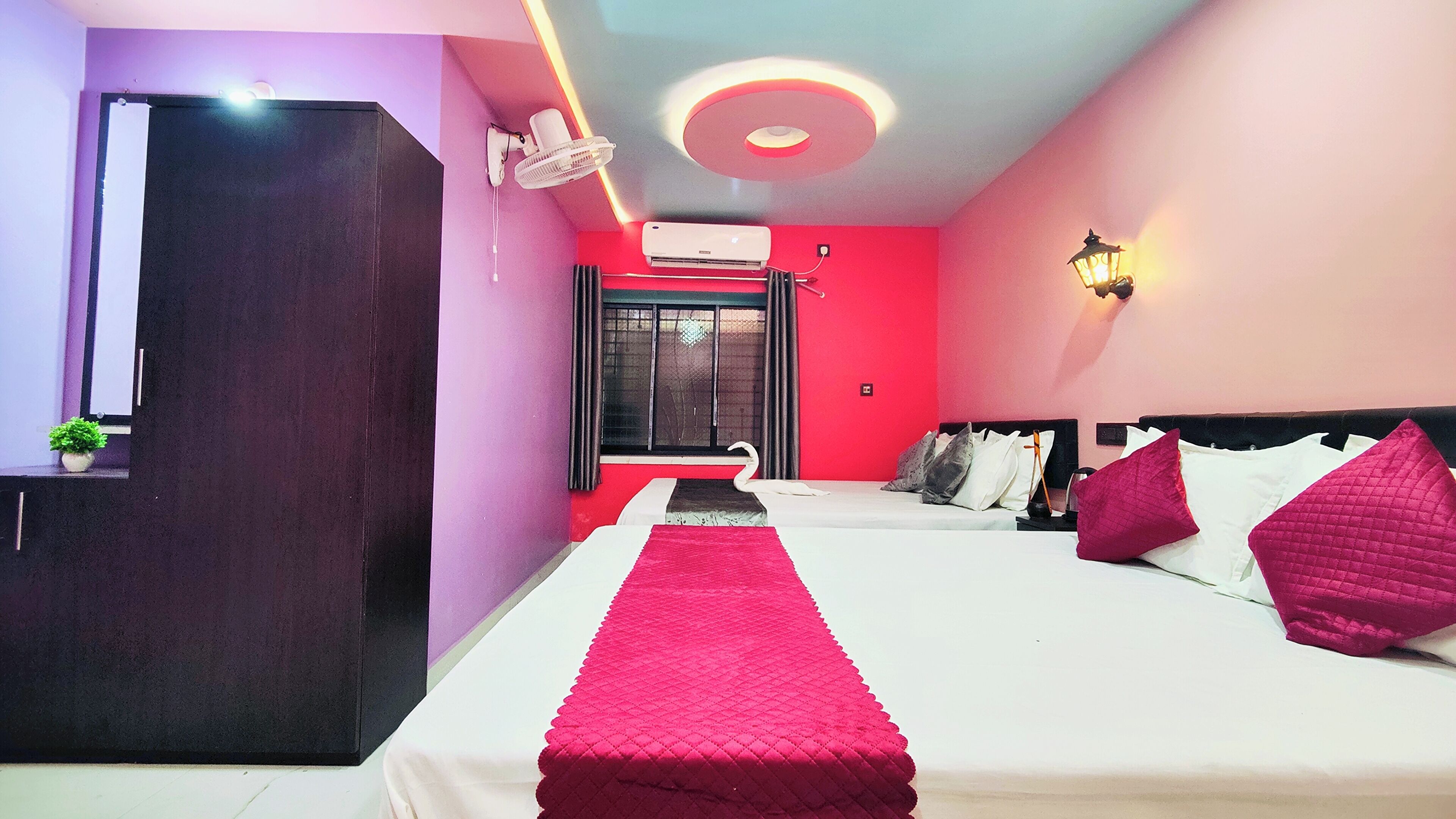 A hotel room with a bed, bedside table, lamp, and a window with curtains.
