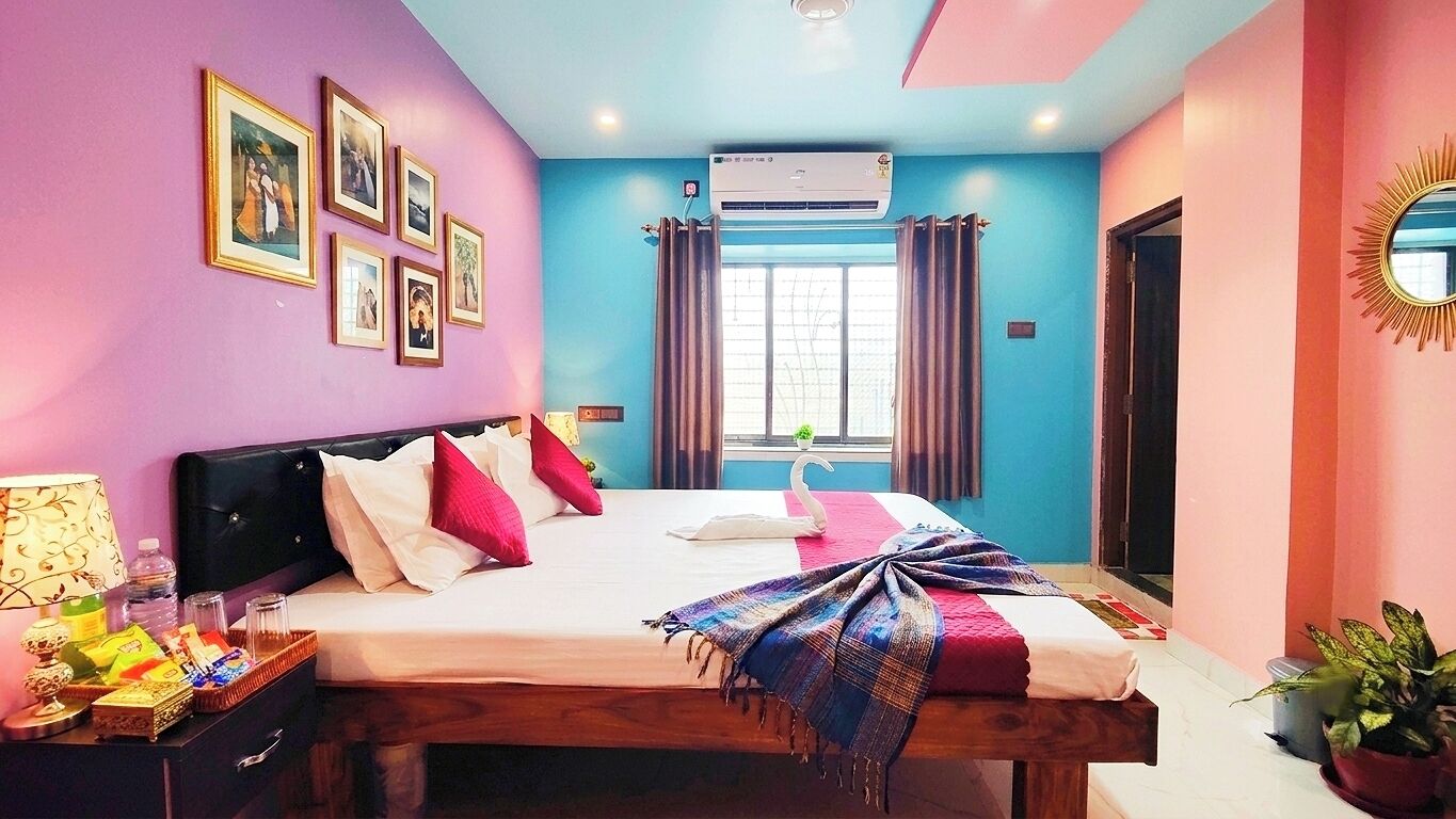 A bedroom with a bed, bedside tables, a window with curtains, and a wall-mounted air conditioner.