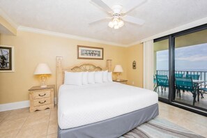 A hotel room with a bed, two bedside tables with lamps, a ceiling fan, a large window with a view, and a balcony with chairs. - Phoenix Vii 7808 3 Bedroom Condo (Orange Beach)
