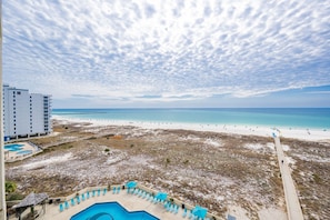 Ein Strandhotel mit Pool, Liegestühlen und Blick auf das Meer.
