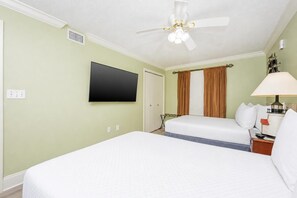 Ein Hotelzimmer mit einem Bett, einem Fernseher, einem Deckenventilator und einer Lampe.