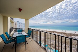 A balcony with a table and chairs, overlooking a beach with a clear sky. - Phoenix Vii 7808 3 Bedroom Condo (Orange Beach)
