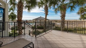 A covered patio area with a view of the beach, palm trees, and a gazebo. - Phoenix Viii 8102 2 Bedroom Condo (Orange Beach)