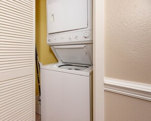 A white washer and dryer unit with a control panel, located in a hallway with a yellow wall and a white door. - Phoenix Viii 8102 2 Bedroom Condo (Orange Beach)