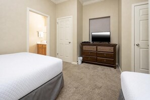 A hotel room with two beds, a dresser, a television, and a door. - Phoenix Viii 8102 2 Bedroom Condo (Orange Beach)