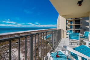 Ein Balkon mit Blick auf den Strand, Sitzgelegenheiten im Freien und ein Poolbereich.