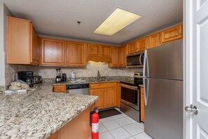 Eine Küche mit Holzausstattung, Granit Arbeitsplatten, einem Edelstahlkühlschrank, einer Mikrowelle, einem Backofen und einem Geschirrspüler.