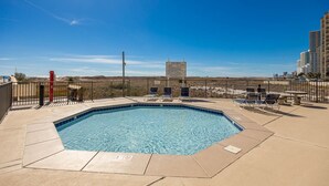 A rectangular pool with a tiled edge, surrounded by a fence, and several lounge chairs. - Phoenix Viii 81206 3 Bedroom Condo (Orange Beach)