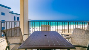 A balcony with a table and chairs overlooking a beach. - Phoenix Viii 81206 3 Bedroom Condo (Orange Beach)