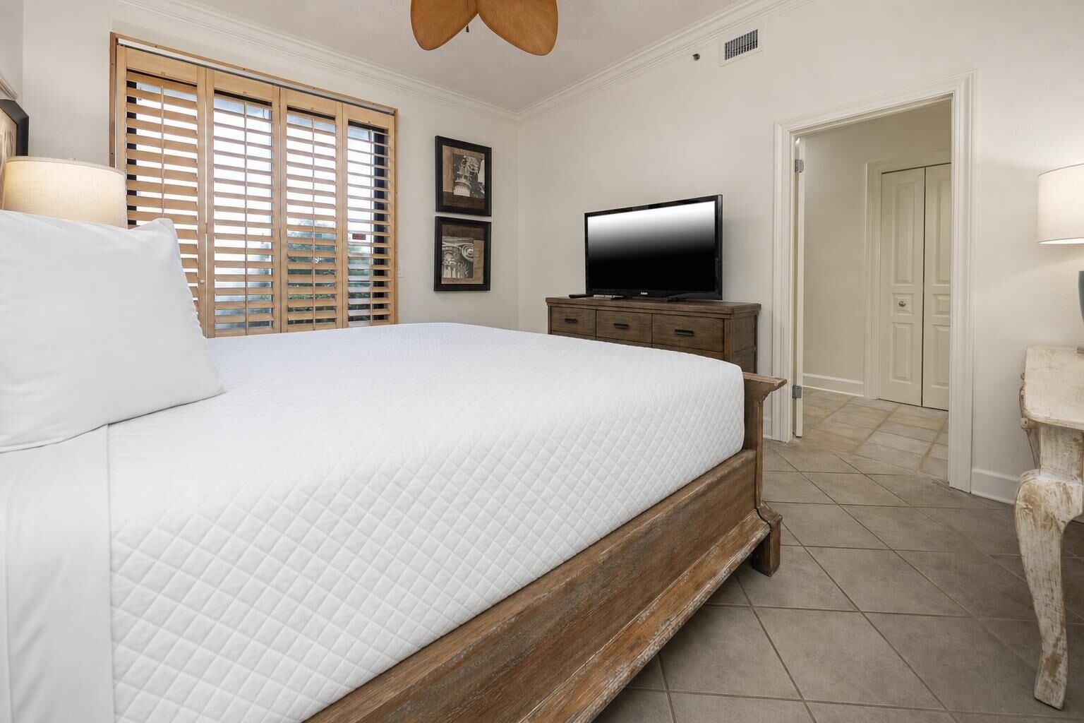 Ein Schlafzimmer mit Bett, Fernseher, Kommode und Tür.