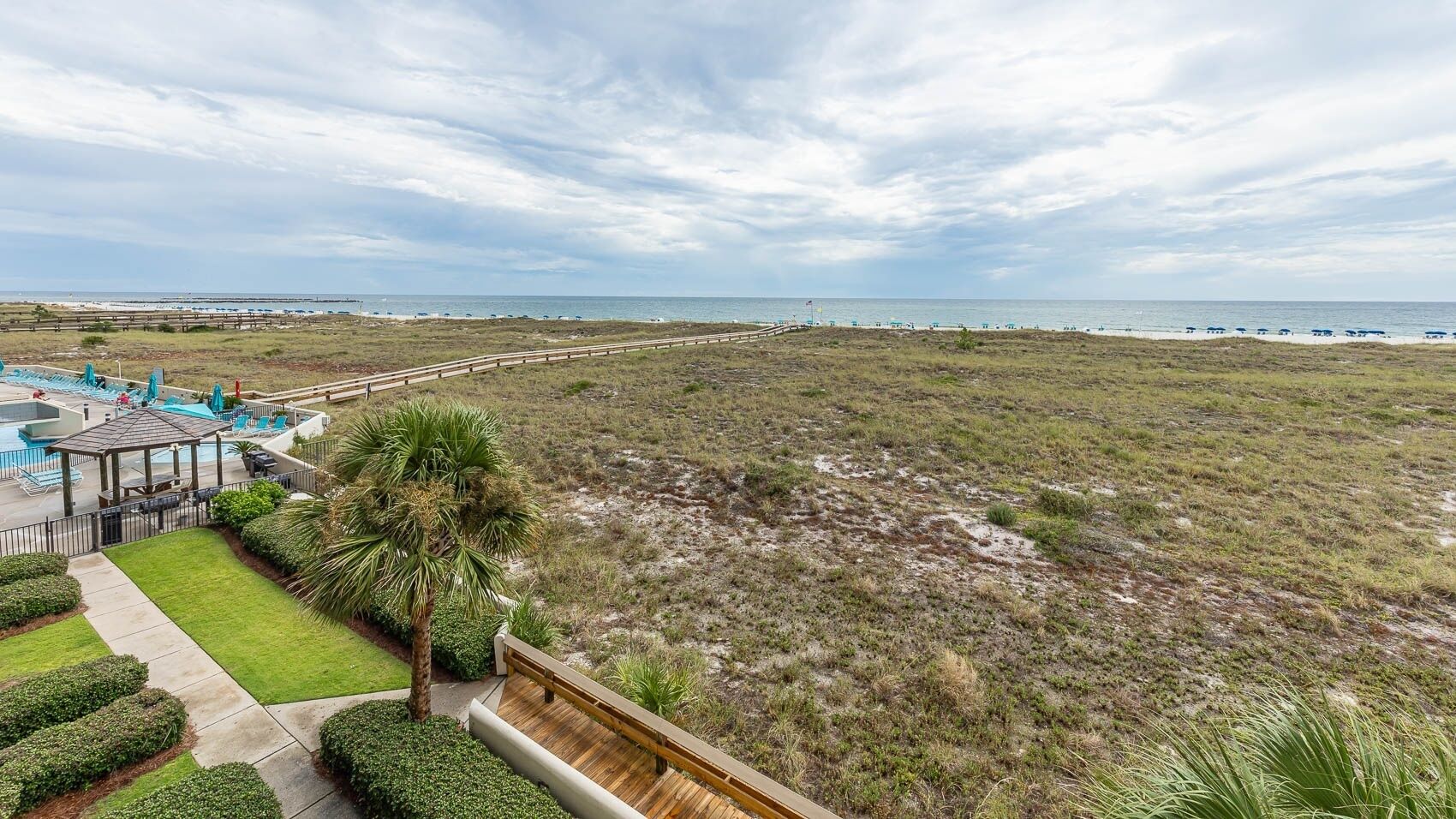 A beachside hotel with a pool, lounge chairs, and a view of the ocean.