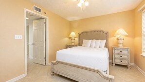 A bedroom with a bed, two bedside tables, a nightstand, a door, and a ceiling fan. - Phoenix Vii 7201 3 Bedroom Condo (Orange Beach)