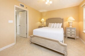 A bedroom with a bed, two bedside tables, a nightstand, a door, and a ceiling fan. - Phoenix Vii 7201 3 Bedroom Condo (Orange Beach)