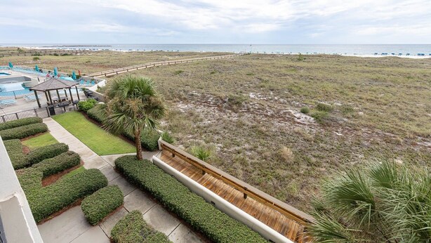 A resort with a pool, lounge chairs, a wooden deck, and a view of the beach. - Phoenix Vii 7201 3 Bedroom Condo (Orange Beach)
