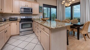 A kitchen with a large island, a microwave, a toaster, and a stove. - Phoenix Vii 7117 3 Bedroom Condo (Orange Beach)