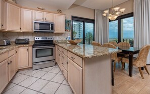 A kitchen with a large island, a microwave, a toaster, and a stove. - Phoenix Vii 7117 3 Bedroom Condo (Orange Beach)