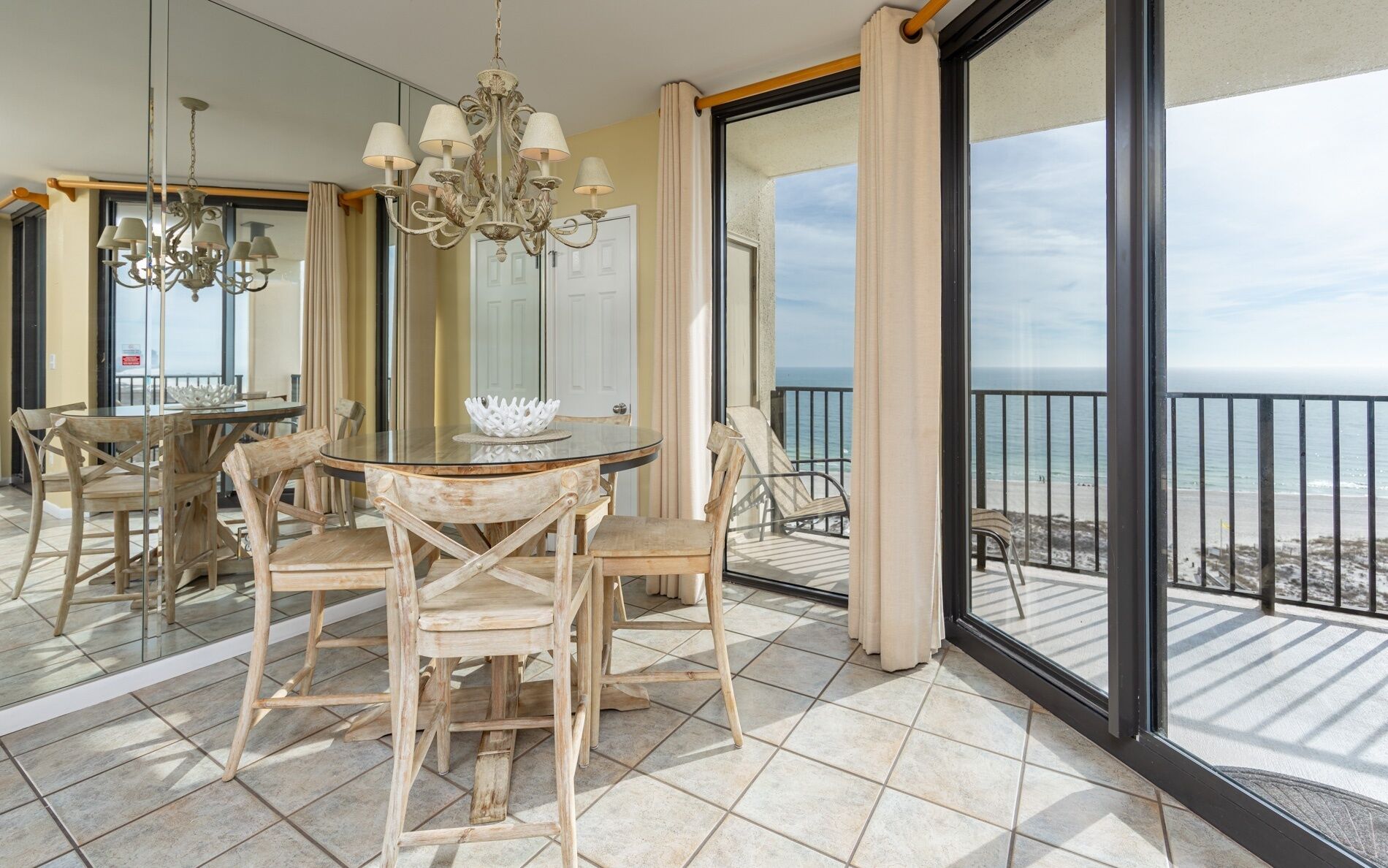 Ein Balkon mit Esstisch und Stühlen, einer Kandelaber und Blick auf das Meer.