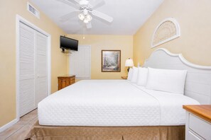 A hotel room with a bed, a ceiling fan, a television, a painting, and a nightstand. - Phoenix Viii 8905 1 Bedroom Condo (Orange Beach)