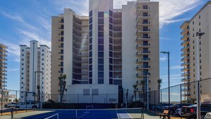 Um hotel com vários andares, varandas, área de estacionamento e céu azul.