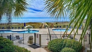 Uma área de piscina com várias piscinas, uma fonte de água e vista para a praia.