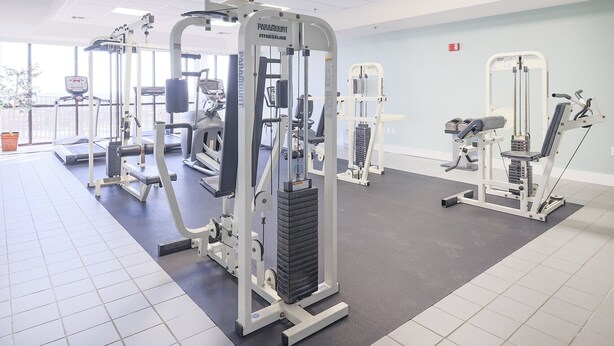 A fitness center with various exercise machines, including a squat rack and a leg press. - Phoenix Viii 81103 3 Bedroom Condo (Orange Beach)